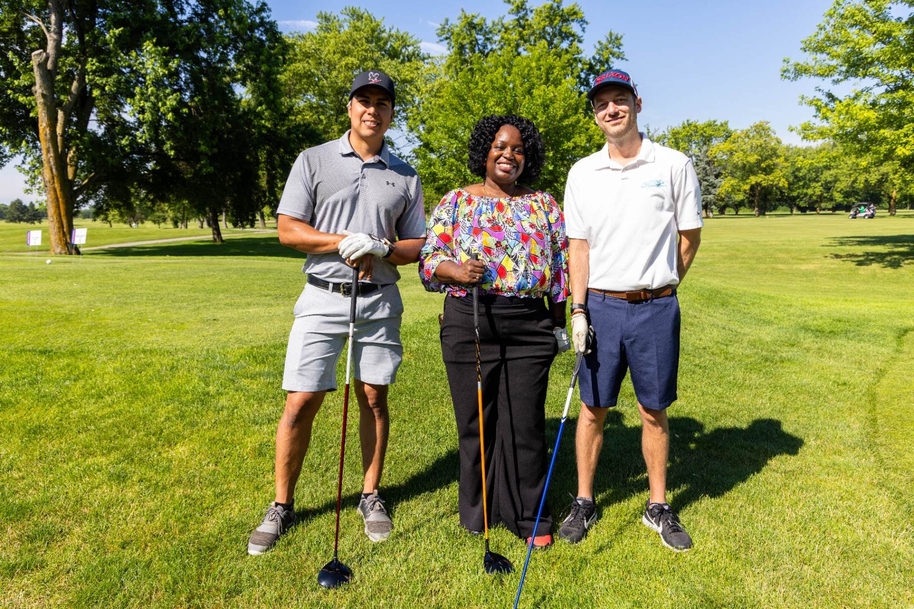 Threesome posing on the fairway with clubs